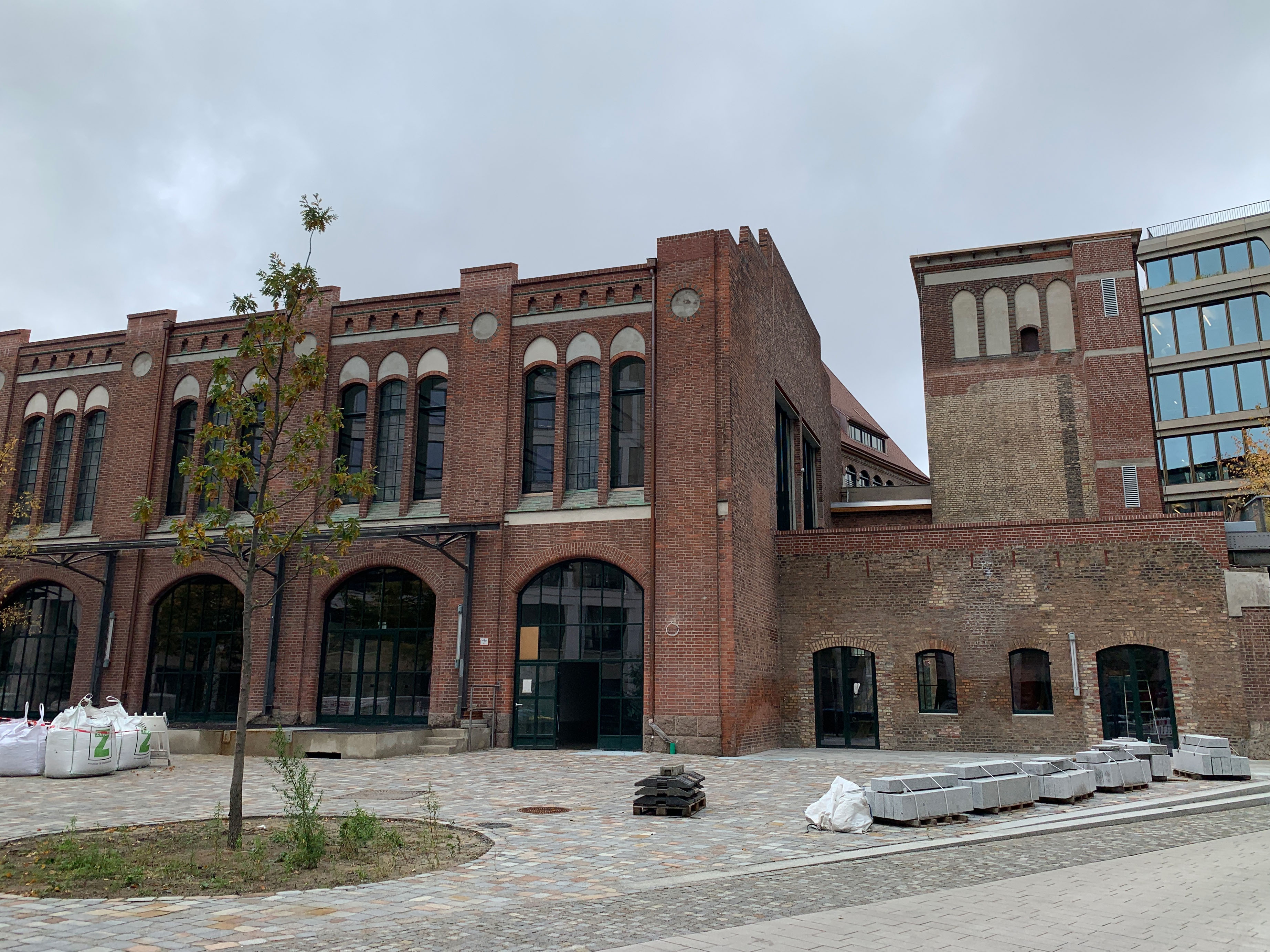 Brick building with large arched windows and paved forecourt, exterior view of the former packing room.