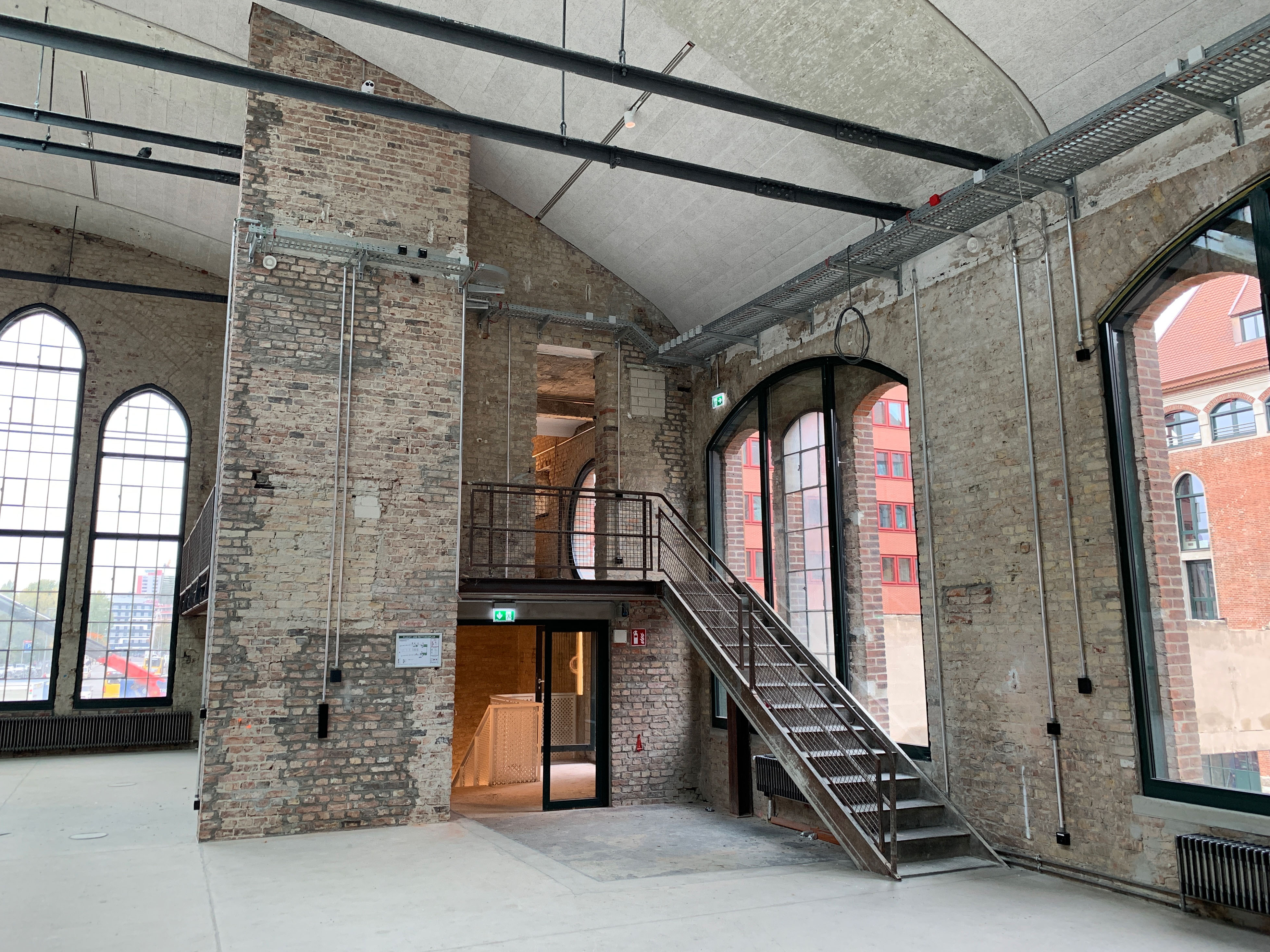 Interior shot with brick walls, metal staircase, and tall windows, industrial architecture of the renovated packing room.