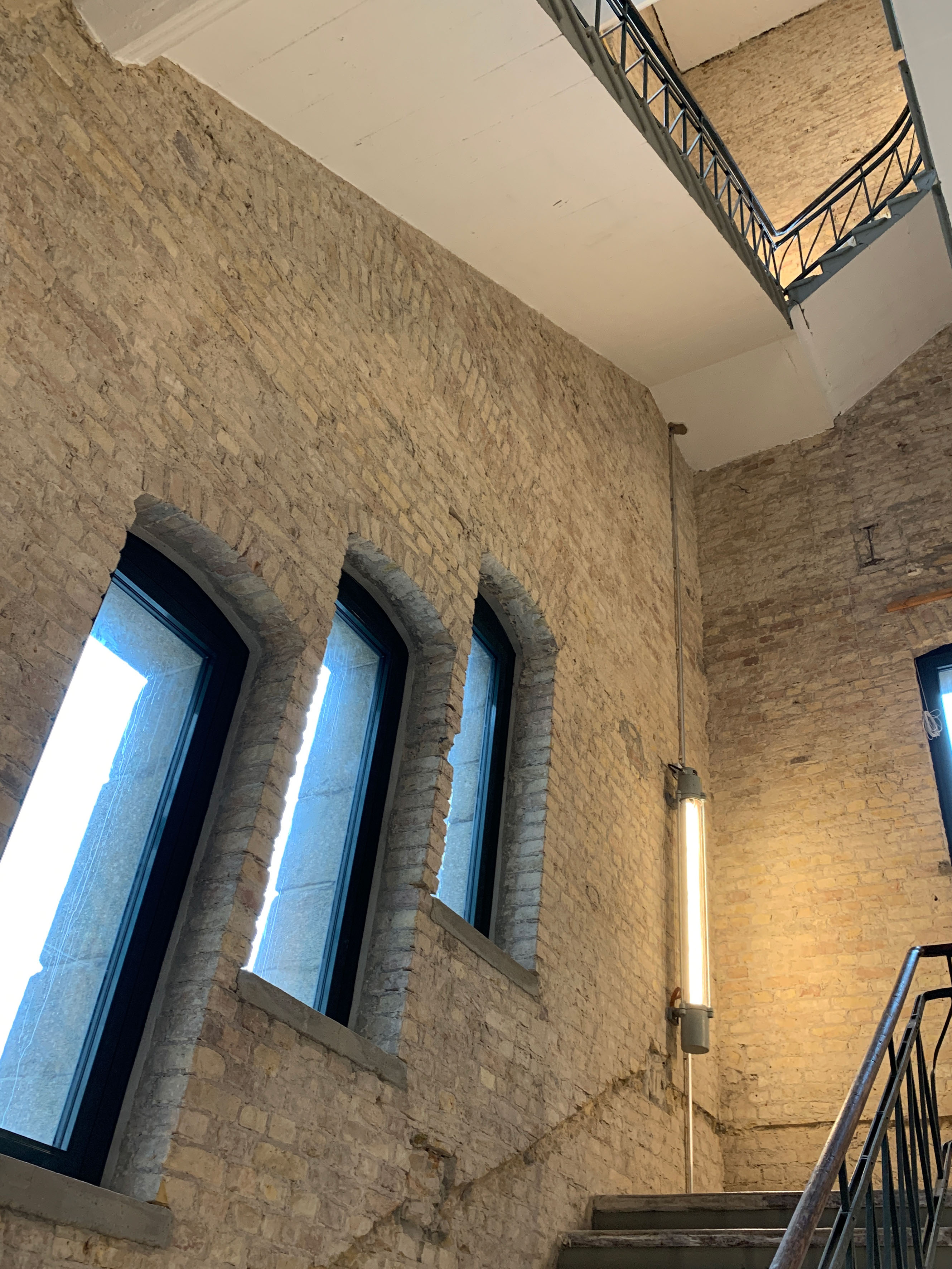 Staircase with exposed brick walls and skylight, industrial architecture with distinctive lighting.