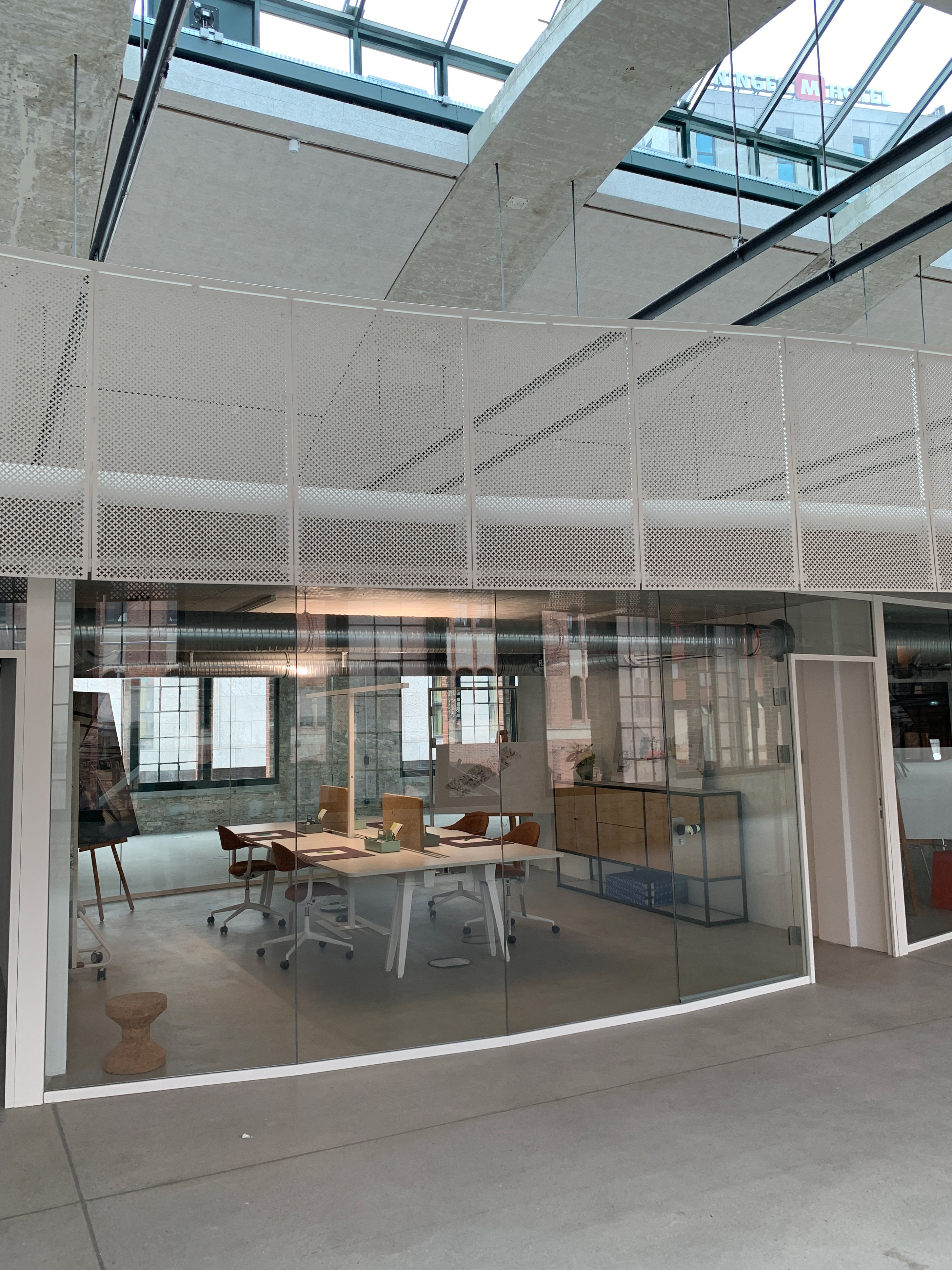 Modern meeting room with glass walls, large windows, and industrial-style wood and metal elements.