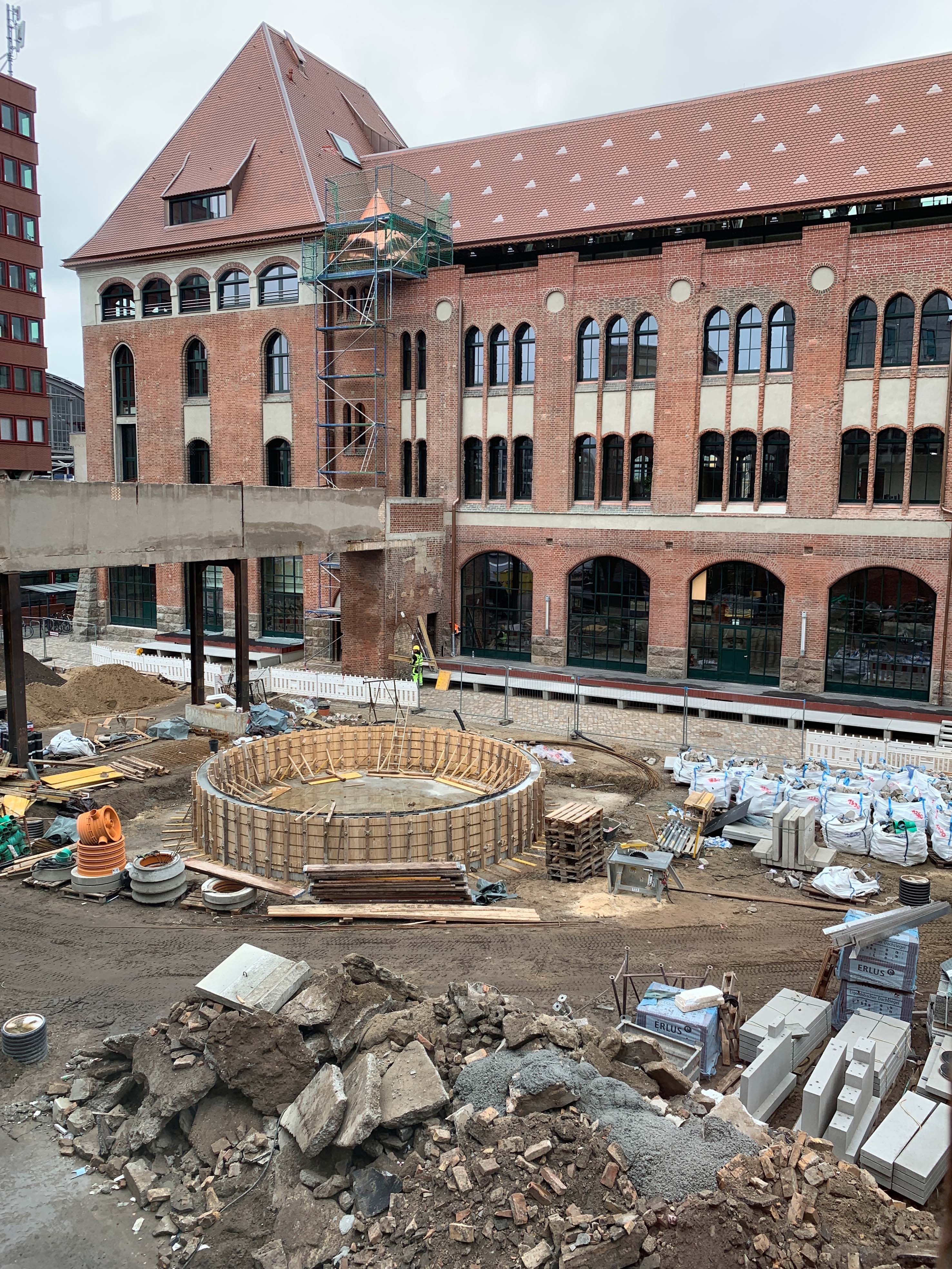Construction site scene with rotunda and scaffolding in the foreground, historic brick facade in the background.