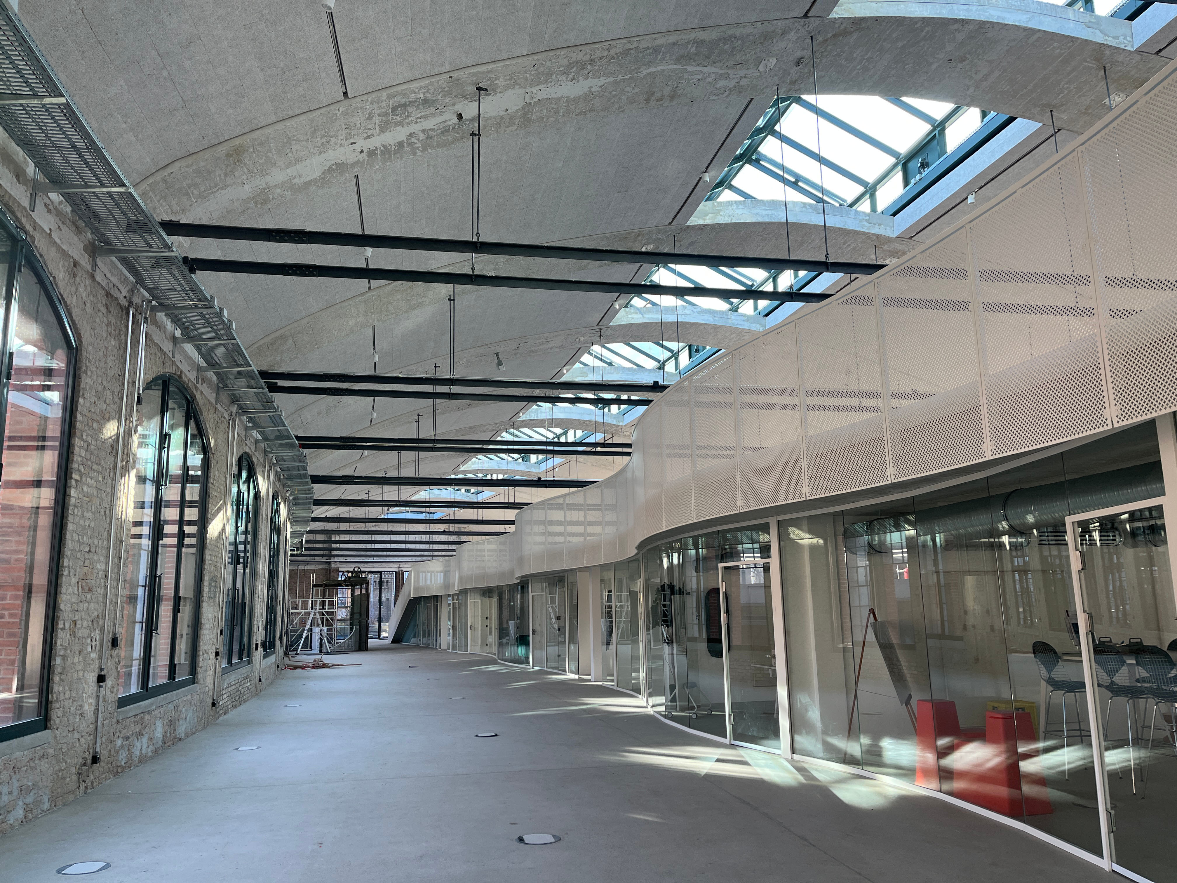 Exterior view of construction progress at Berlin's Postbahnhof with a glimpse of the modern interior featuring glass fronts and vaulted ceilings.