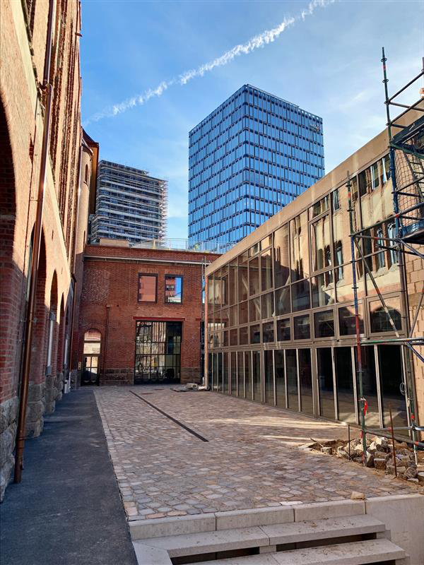 Exterior view of construction progress at the Postbahnhof Berlin with a view of the paved courtyard.