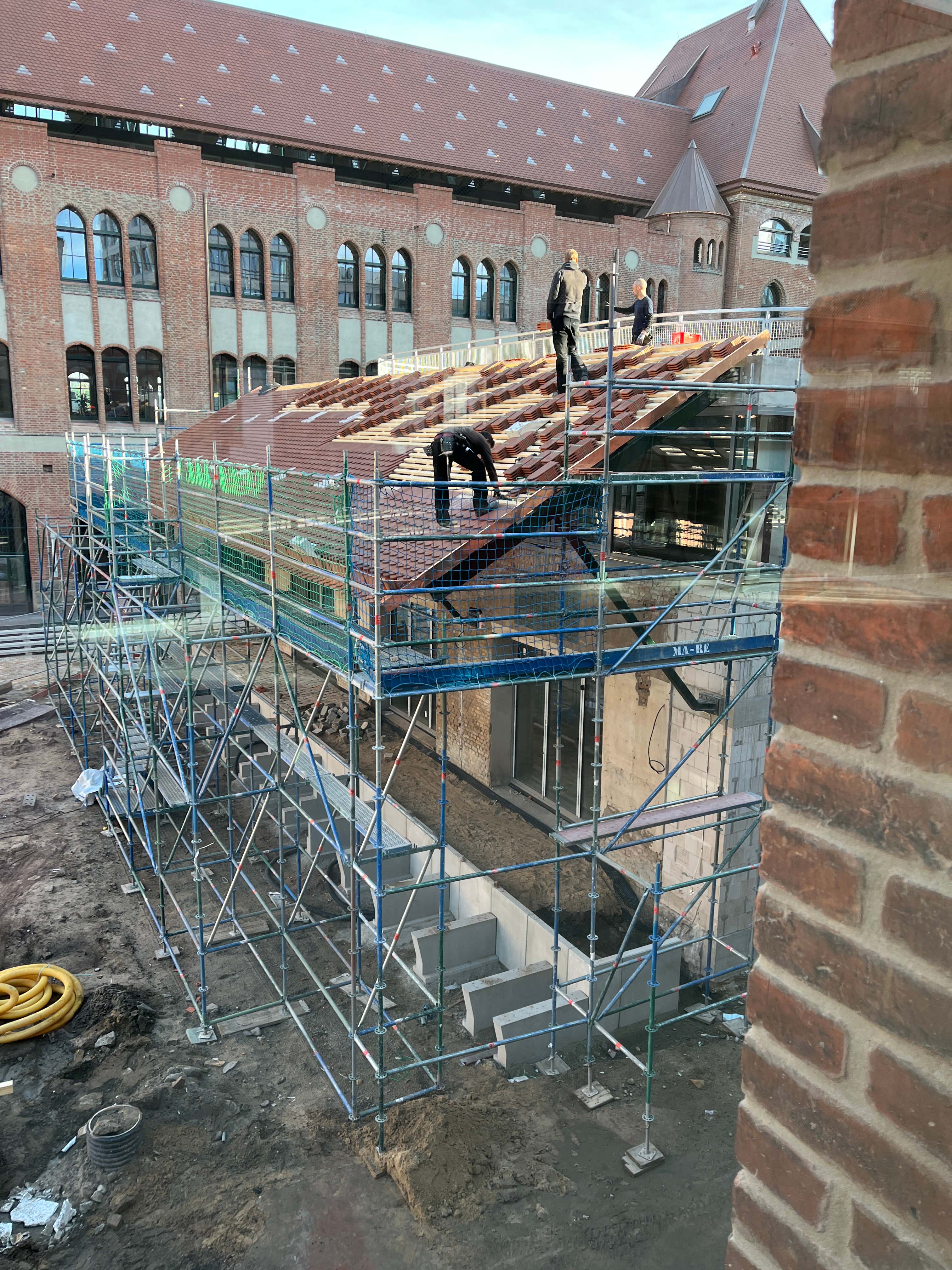 Exterior view of construction progress at Berlin's Postbahnhof with a view of the Beutel.