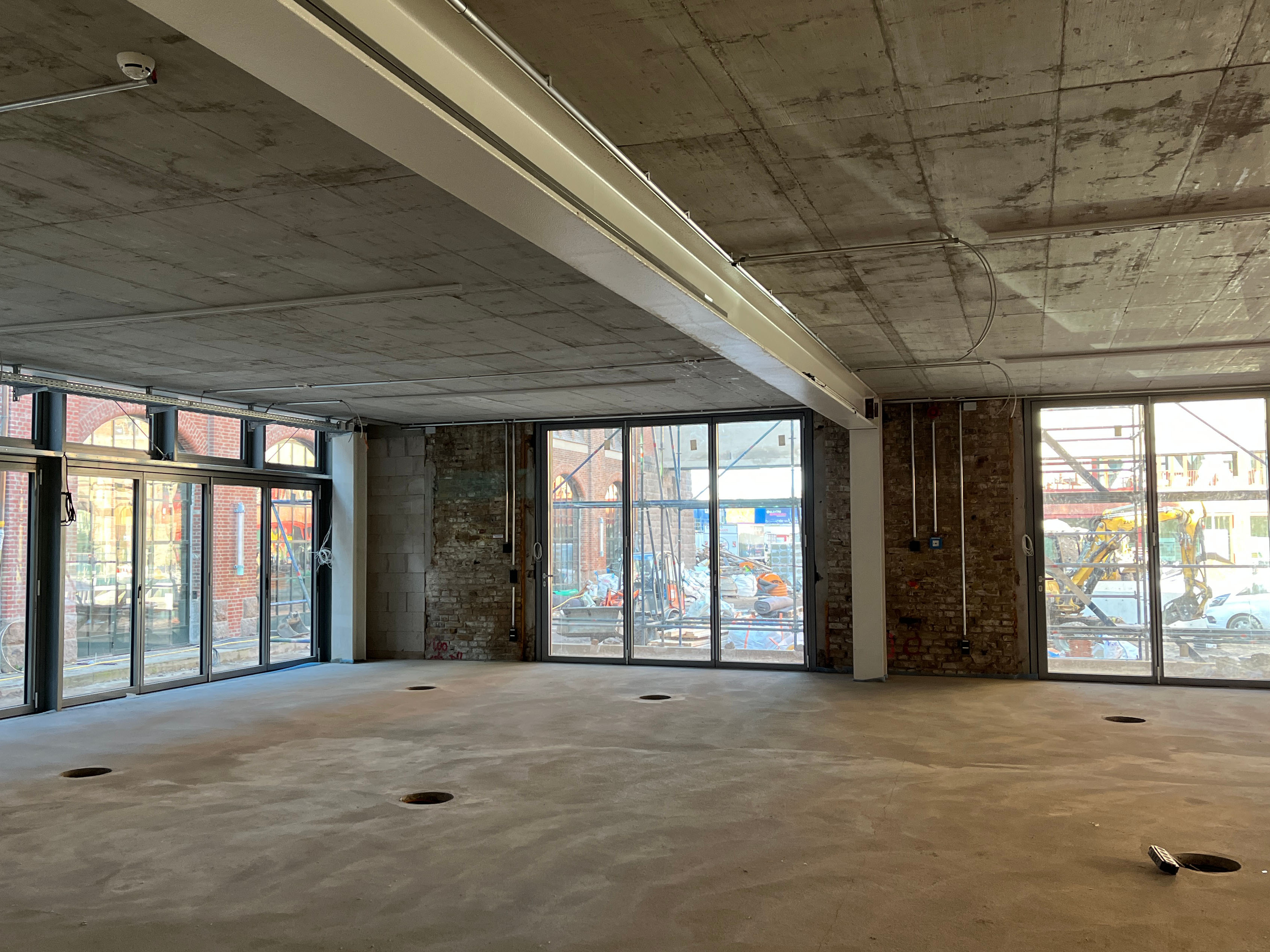 Interior view of construction progress at the Postbahnhof Berlin with a view into the open interior with large window fronts.