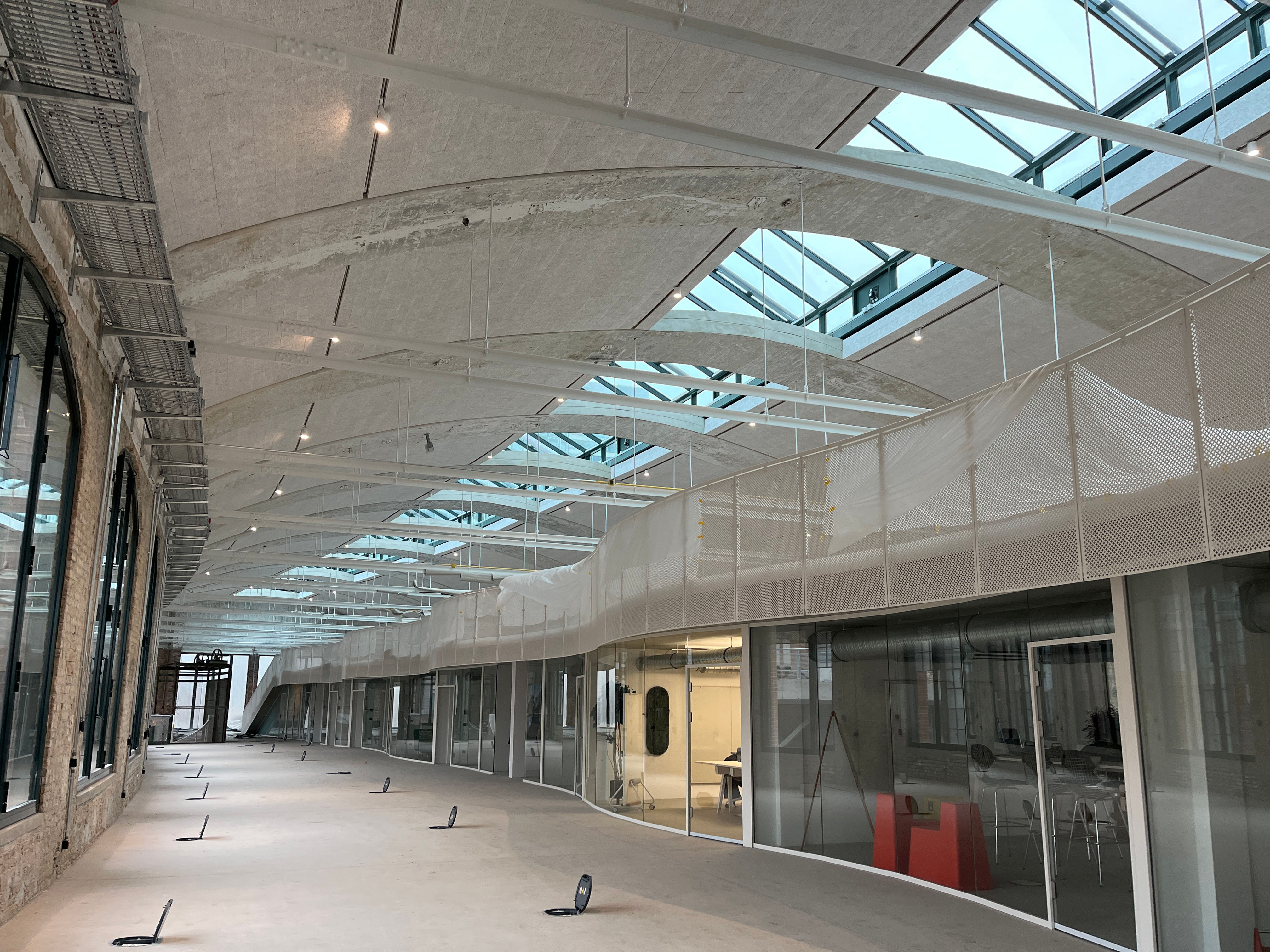 Long interior of the entrance packing chamber with glass ceiling and construction site equipment.