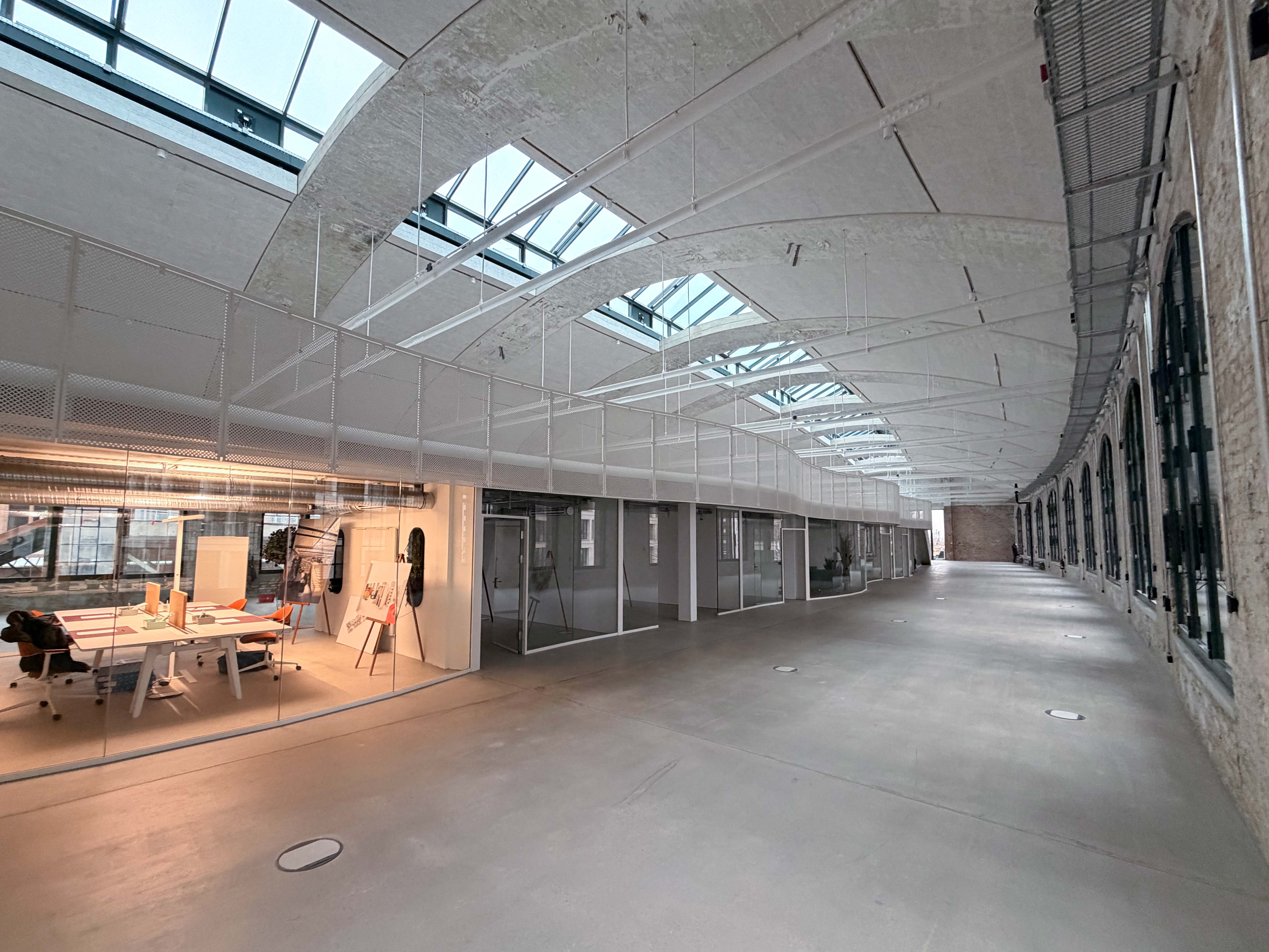 Der Baufortschritt im Postbahnhof Berlin zeigt die Eingangspackkammer im 1. OG mit großzügiger Raumtiefe, Oberlichtern und angrenzenden Arbeitsbereichen.